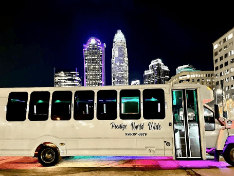 Concert transportation service in Charlotte with party bus near the city skyline at night